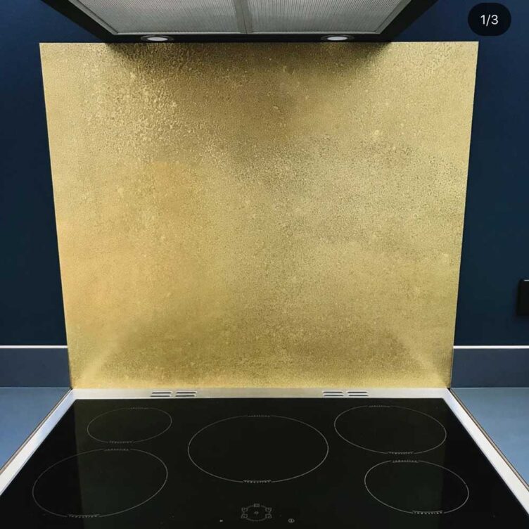 Aged brass kitchen splashback behind hob