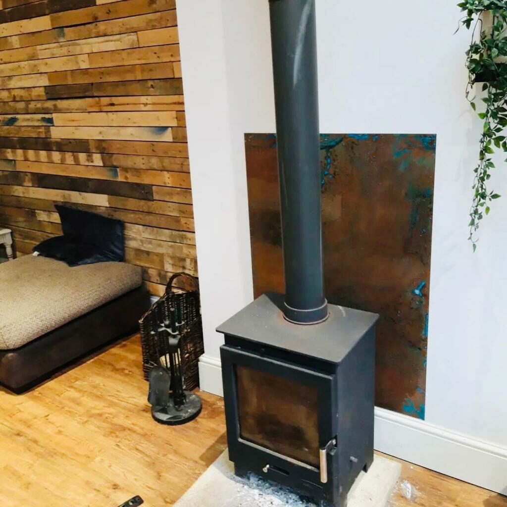 Aged copper sheet behind wood burning stove