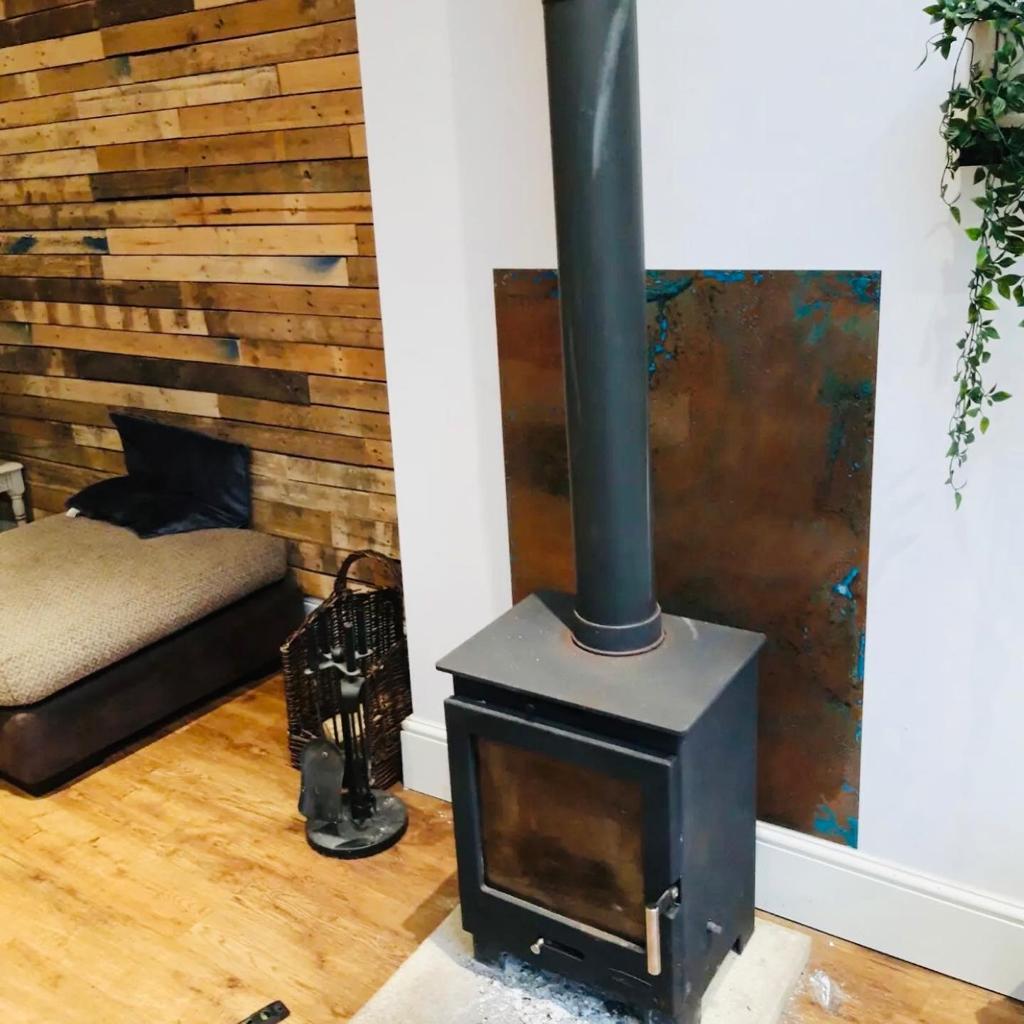 Aged copper sheet behind wood burning stove