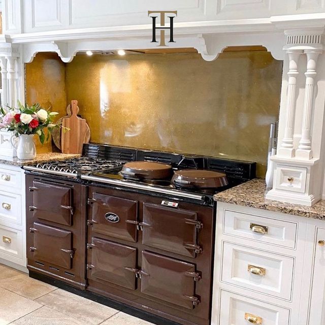 gold splashback in white kitchen behind brown AGA