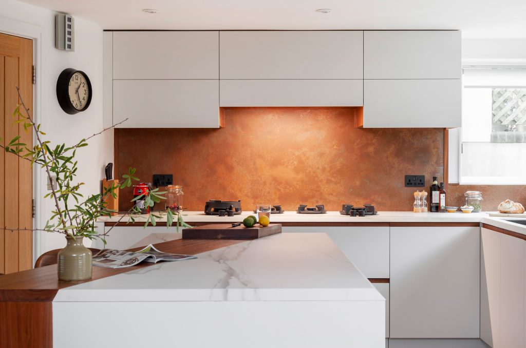 aged copper backsplash with plug cutouts behind kitchen hob